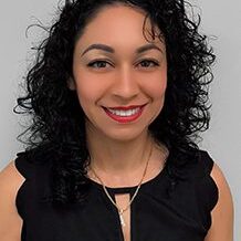 Smiling woman with curly hair and red lipstick wearing a black top.